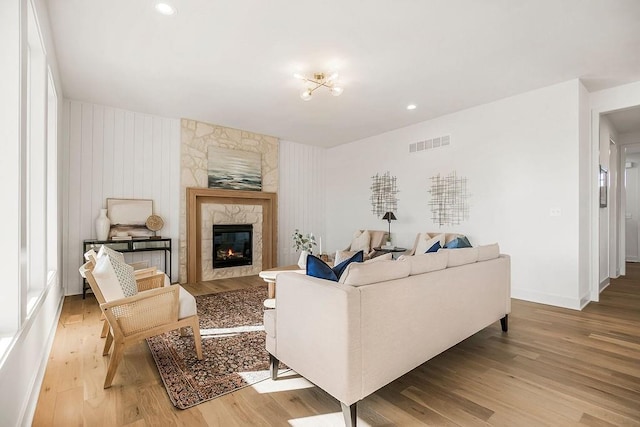 living room with baseboards, light wood-style floors, visible vents, and a large fireplace