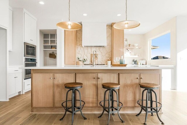 kitchen featuring a sink, light wood-style floors, light countertops, stainless steel oven, and built in microwave