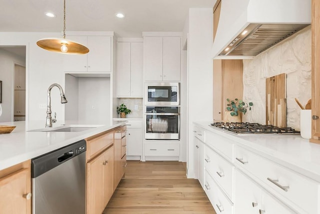 kitchen featuring premium range hood, light wood-style flooring, a sink, stainless steel appliances, and light countertops