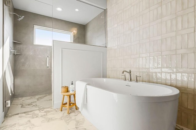 bathroom featuring marble finish floor, tile walls, and a shower stall