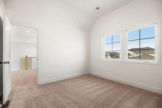 carpeted empty room featuring visible vents, lofted ceiling, and baseboards