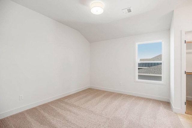 additional living space with visible vents, light colored carpet, baseboards, and vaulted ceiling