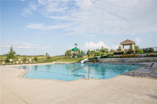 pool with a gazebo, a patio, fence, and a water slide