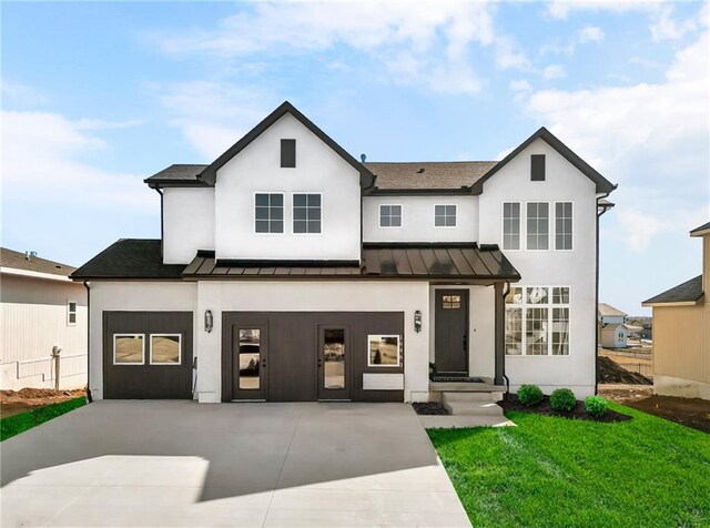 modern farmhouse style home featuring a standing seam roof and concrete driveway