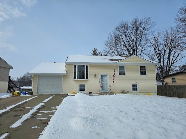 split foyer home with entry steps, an attached garage, and fence