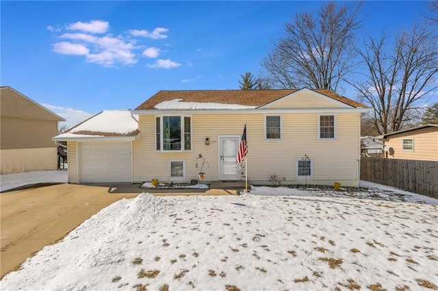 raised ranch featuring fence, driveway, and an attached garage