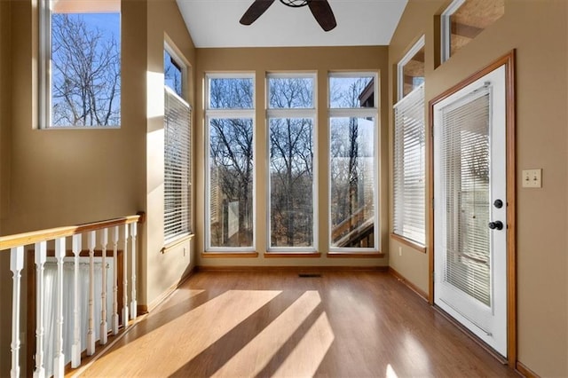 unfurnished sunroom with lofted ceiling, ceiling fan, and visible vents