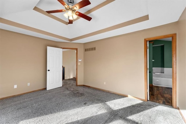 unfurnished bedroom with carpet floors, visible vents, and a tray ceiling