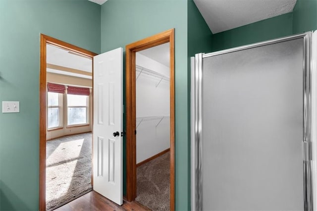 full bathroom featuring a walk in closet, a shower stall, and baseboards