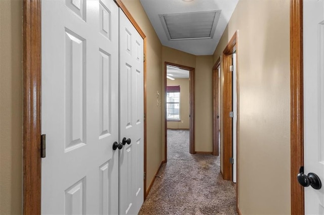 hall with attic access, carpet, and baseboards