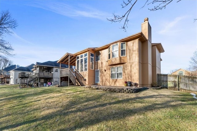 rear view of property with a chimney, a yard, stairs, fence, and a wooden deck