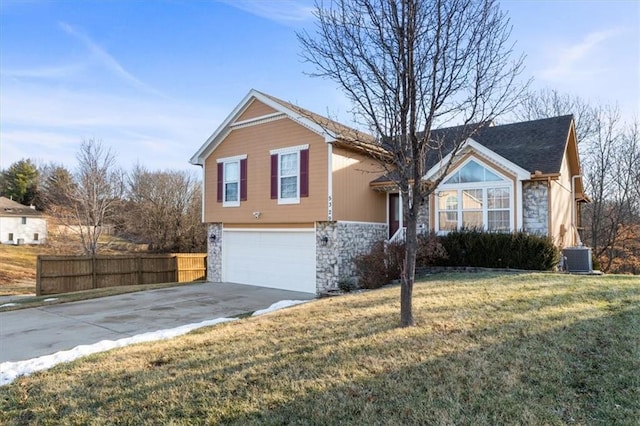 view of front facade with an attached garage, fence, stone siding, concrete driveway, and a front yard