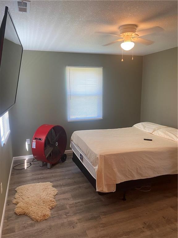 200 Ramsey Dr, Craig, MO 64437 - bedroom featuring dark wood-style flooring, visible vents, a ceiling fan, a textured ceiling, and baseboards