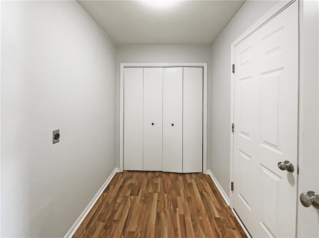 hall featuring dark wood-style flooring and baseboards