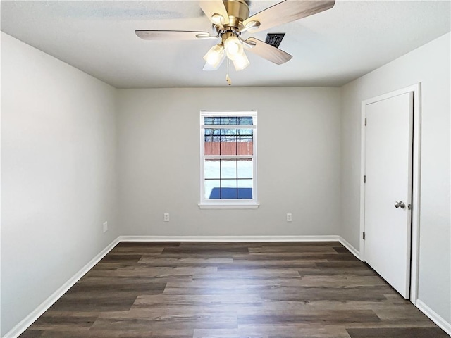 spare room with dark wood-type flooring, a ceiling fan, and baseboards