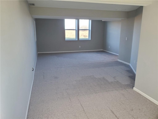 empty room with carpet, visible vents, and baseboards