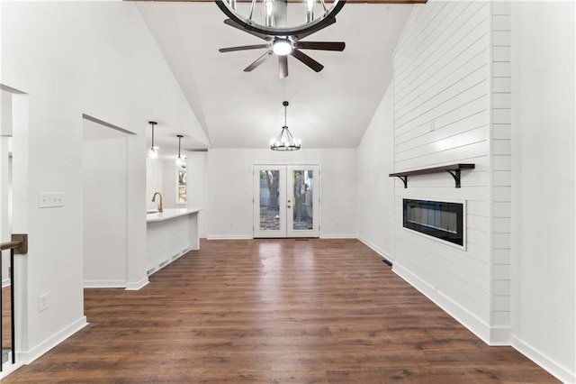 unfurnished living room with dark wood-style floors, a fireplace, high vaulted ceiling, and baseboards