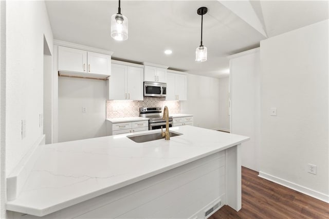 kitchen featuring light stone counters, backsplash, appliances with stainless steel finishes, white cabinetry, and a sink