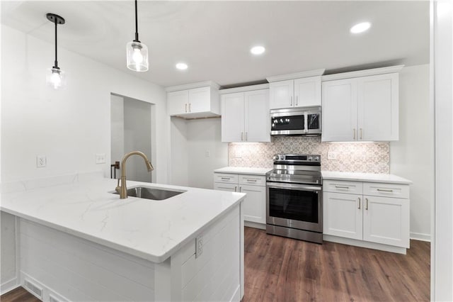 kitchen featuring dark wood-style flooring, stainless steel appliances, white cabinetry, a sink, and a peninsula