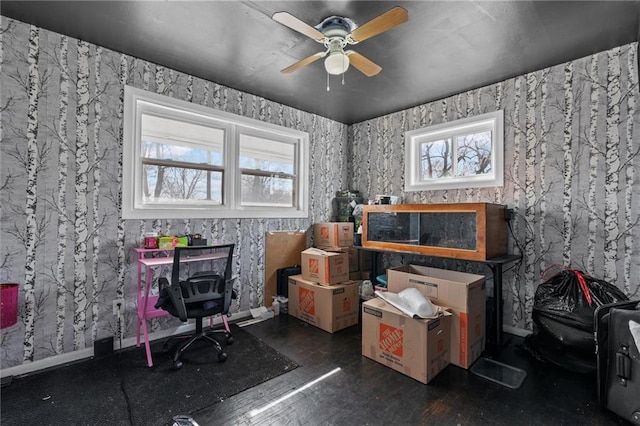 office area featuring dark wood-type flooring, a ceiling fan, baseboards, and wallpapered walls