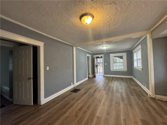 unfurnished room featuring a textured ceiling, dark wood-type flooring, visible vents, baseboards, and crown molding