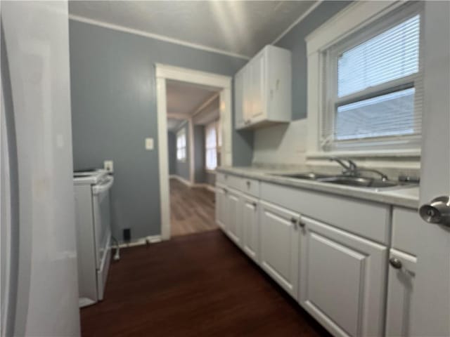 kitchen featuring washer / clothes dryer, white cabinetry, light countertops, and a sink