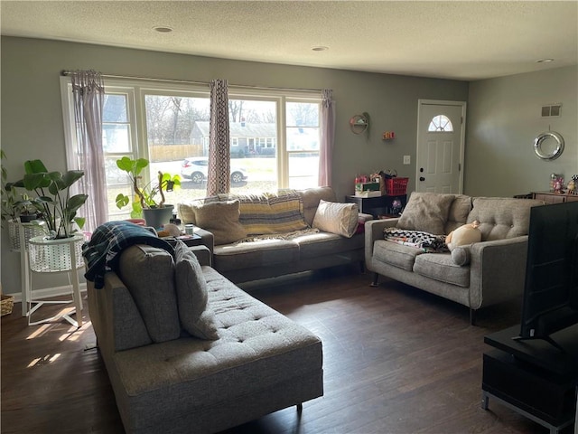 living room with dark wood finished floors, visible vents, and a textured ceiling