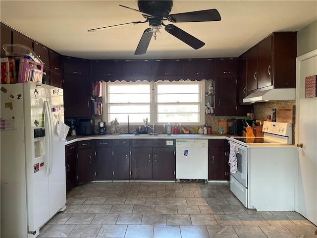 kitchen with under cabinet range hood, white appliances, light countertops, and a sink