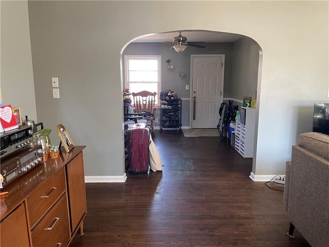 hall featuring dark wood finished floors, baseboards, and arched walkways