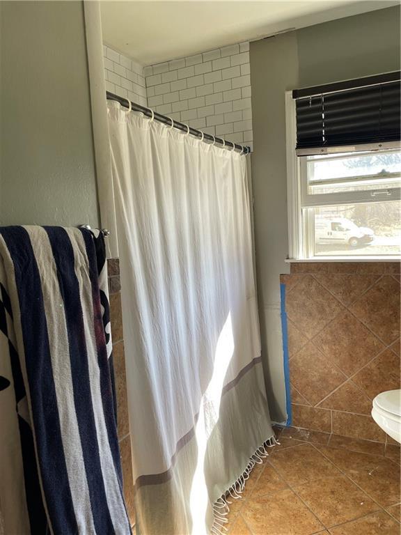 bathroom with a shower with shower curtain, tile patterned floors, and tile walls