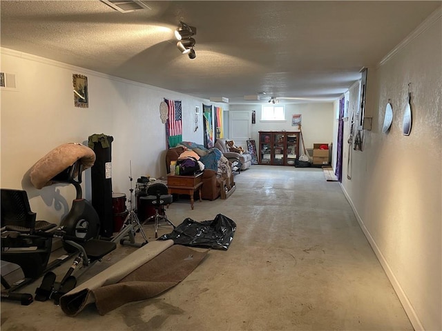 interior space with visible vents, ornamental molding, a textured ceiling, baseboards, and a textured wall