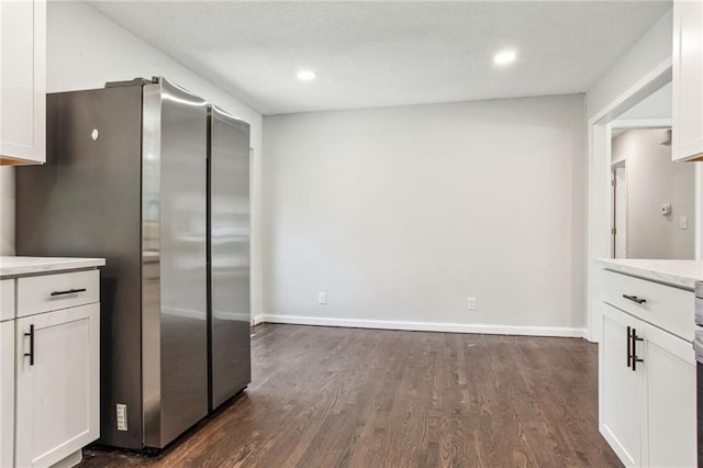 kitchen with light countertops, freestanding refrigerator, white cabinetry, and dark wood-type flooring