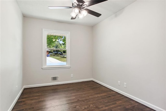 spare room with dark wood-style flooring, visible vents, and baseboards