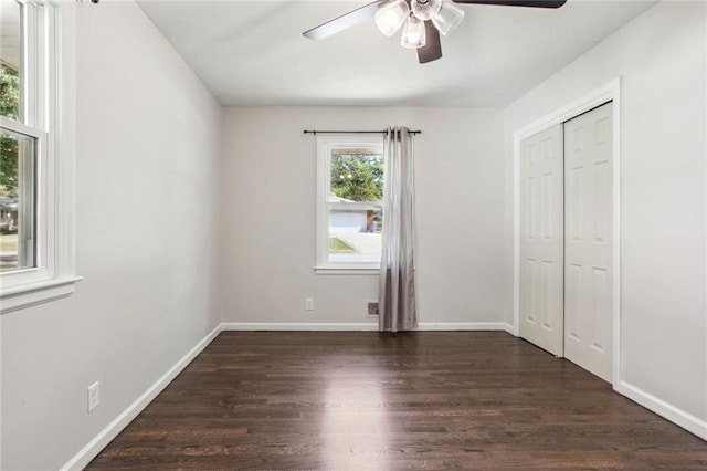 unfurnished bedroom featuring ceiling fan, dark wood-style flooring, a closet, and baseboards