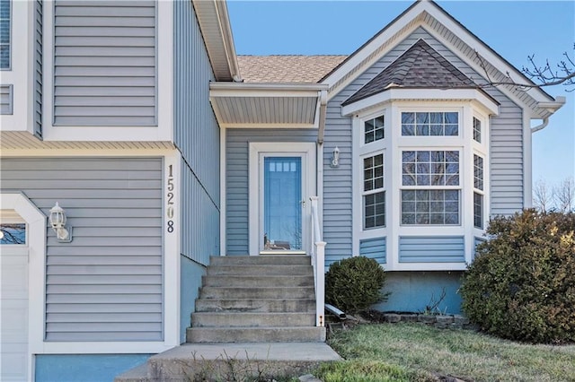 view of exterior entry with a shingled roof