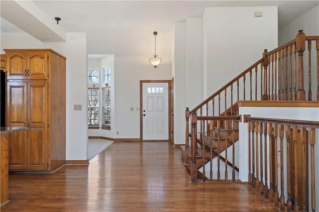 foyer featuring baseboards, dark wood finished floors, stairway, and a high ceiling