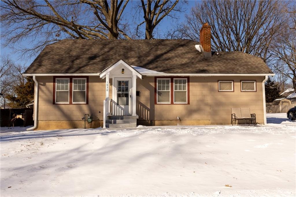 view of front of property featuring entry steps, roof with shingles, and a chimney