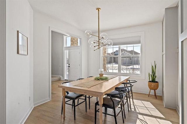 dining room with baseboards, light wood-type flooring, stairs, and an inviting chandelier