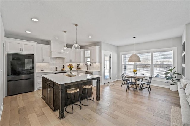 kitchen with tasteful backsplash, a breakfast bar area, light countertops, smart refrigerator, and white cabinetry