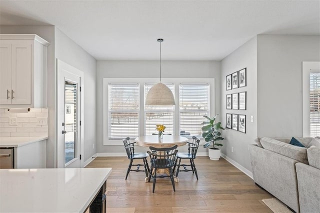 dining room featuring a healthy amount of sunlight, light wood-style flooring, and baseboards