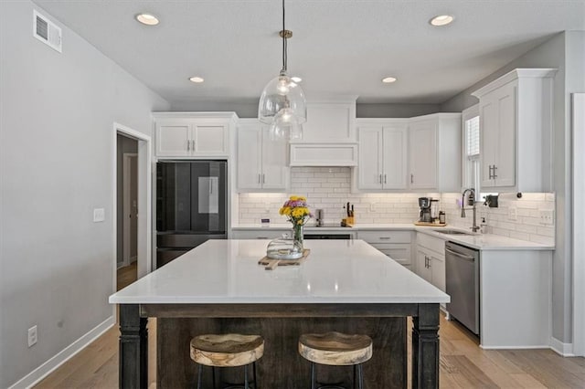 kitchen with white cabinets, a breakfast bar area, a sink, smart refrigerator, and stainless steel dishwasher