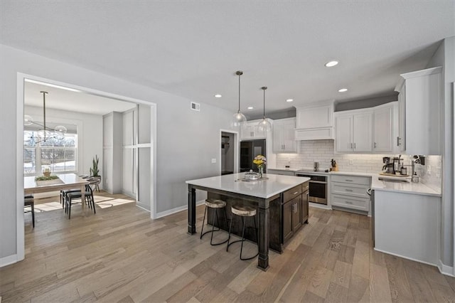 kitchen featuring light countertops, visible vents, decorative backsplash, light wood-type flooring, and oven