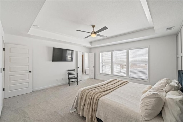 bedroom with light colored carpet, a raised ceiling, visible vents, and baseboards