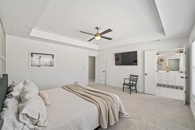 bedroom featuring baseboards, visible vents, a raised ceiling, and light colored carpet