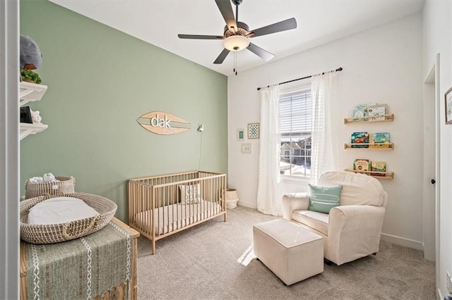 bedroom with carpet, a nursery area, ceiling fan, and baseboards