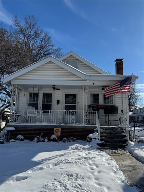 view of front facade featuring covered porch, ceiling fan, and a chimney