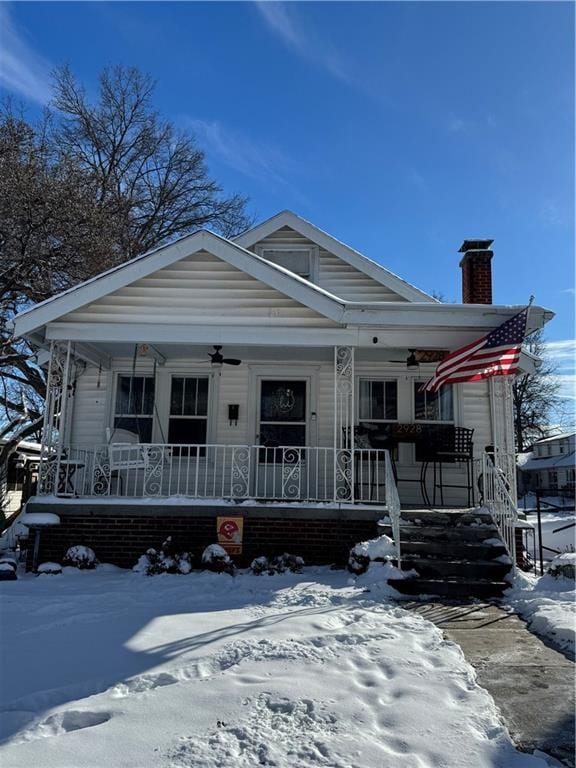 view of front of house with a ceiling fan, covered porch, and a chimney