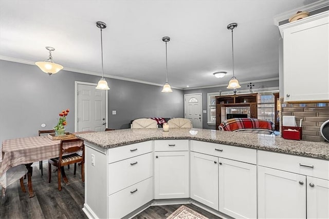 kitchen featuring crown molding, light stone countertops, white cabinetry, and decorative light fixtures