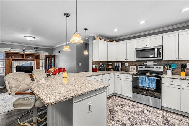 kitchen with appliances with stainless steel finishes, open floor plan, white cabinetry, and a kitchen bar