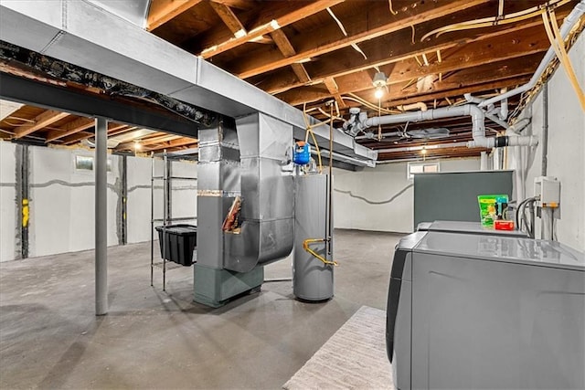 basement featuring water heater, heating unit, and washer and dryer